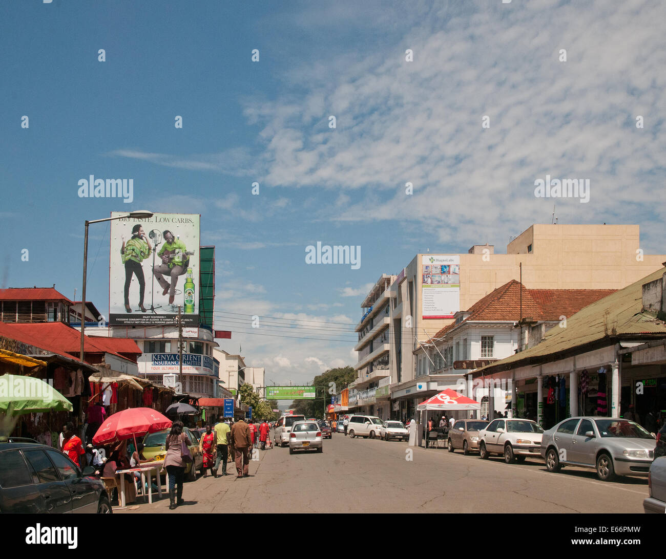 Personnes et de la circulation sur l'avenue Kenyatta Nakuru Kenya Afrique de l'Est avec des panneaux publicitaires et des boutiques modernes vieux fashoned KENYAT Banque D'Images