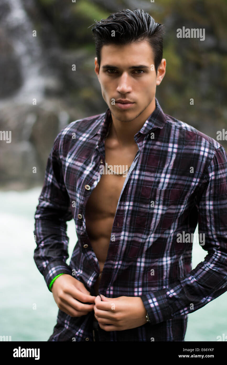 Beau jeune homme près de mountain waterfall avec open shirt déchiré, corps athlétique Banque D'Images