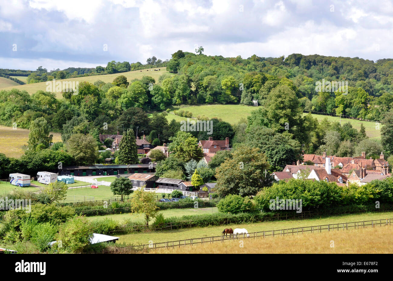 Argent - Chiltern Hills - voir Turville village - toits - Eglise - riding school yard - blanc barrières - collines boisées au-delà Banque D'Images