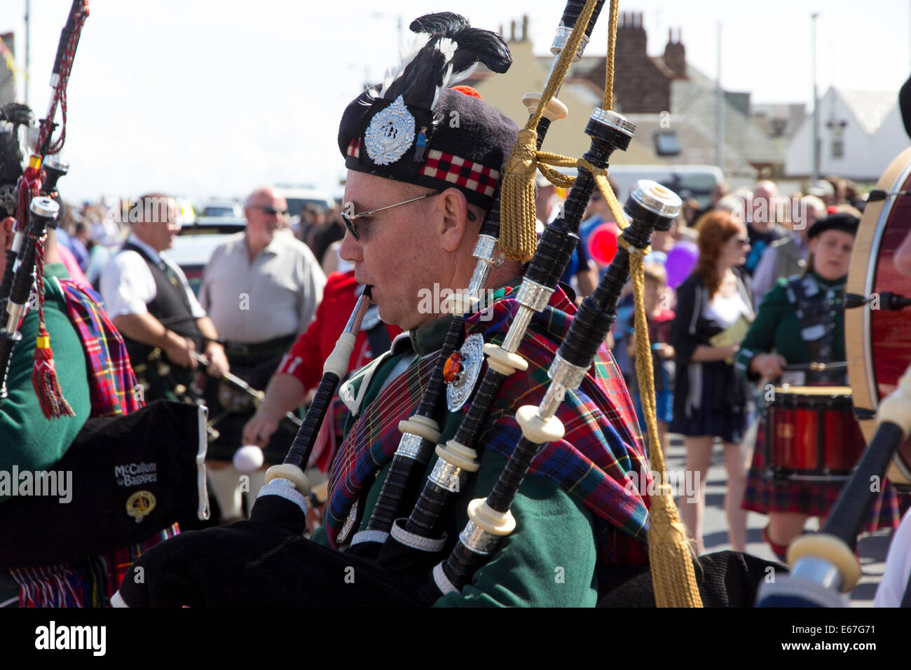 En prélude à l'Highland Games à Brodick, sur l'île d'Arran, bandes en kilt avec cornemuses défilent le long du bord de mer Banque D'Images