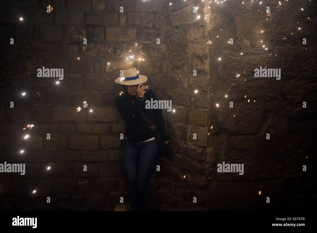 Barcelone, Espagne. 17 août, 2014. Un téléspectateur protéger les charbons et prendre des photos pendant un festival pyrotechnique dans les rues de Barcelone. Correfocs, une vieille tradition catalane où les gens habillés en démons faire exploser des pétards et des fusées éclairantes, prendre part aux célébrations pour le Festival Sant Roc dans le quartier gothique de Barcelone. Crédit : Jordi Boixareu/Alamy Live News Banque D'Images