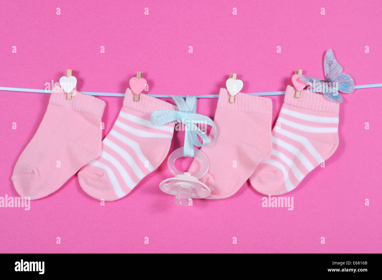 Pépinière bébé fille chaussettes et dummy pacifier hanging from pegs sur une ligne contre un fond rose Banque D'Images