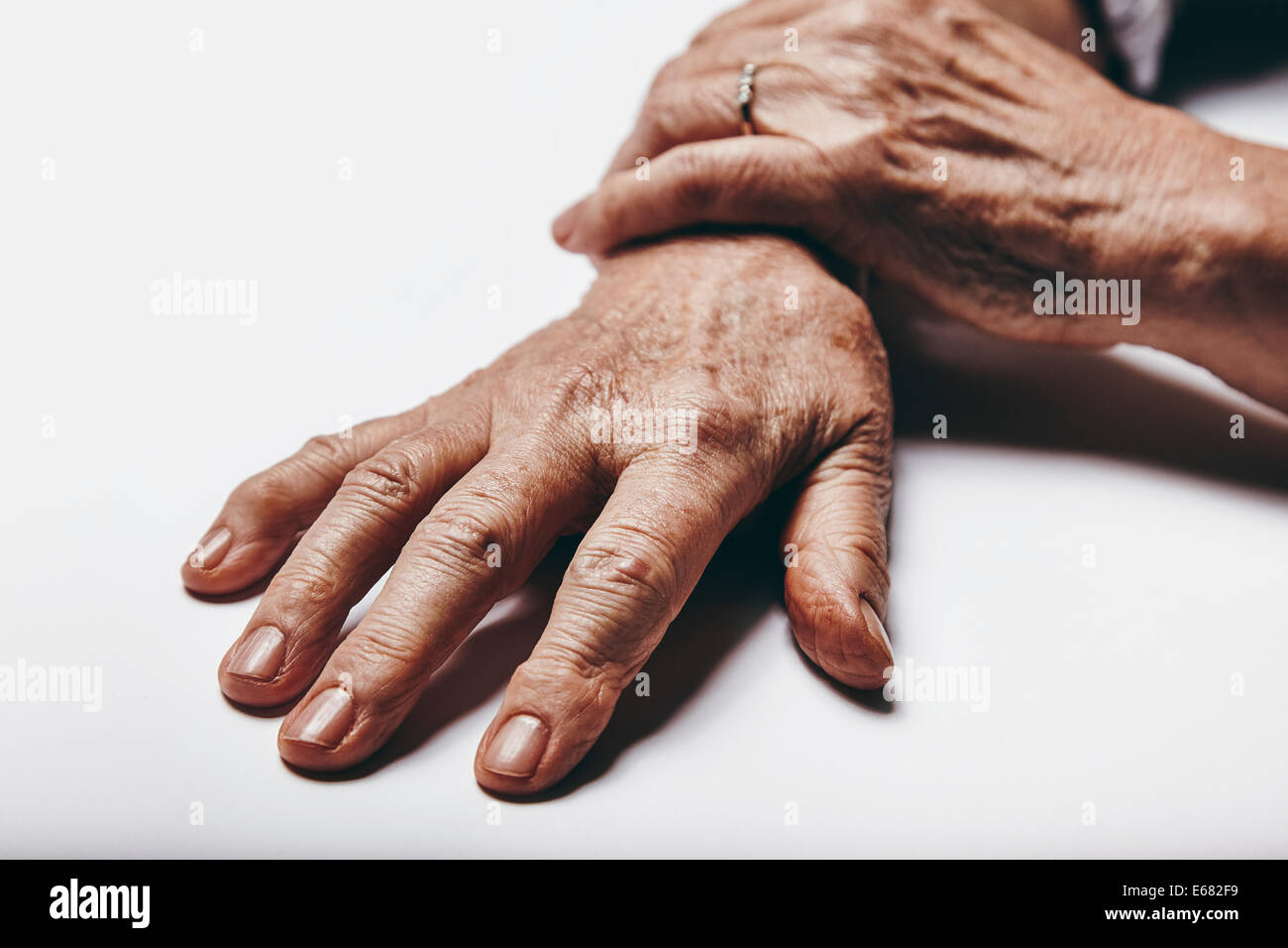 Macro de vieille femme main sur une surface grise. Se concentrer sur les doigts des personnes de sexe féminin. Banque D'Images
