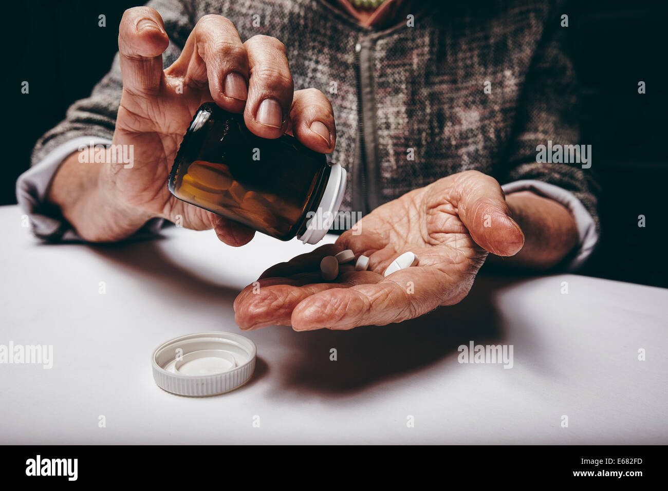 Portrait de femme âgée en prenant des médicaments sur ordonnance à partir de la bouteille de pilules. Les mains de femmes âgées pouring pills sur sa paume whi Banque D'Images