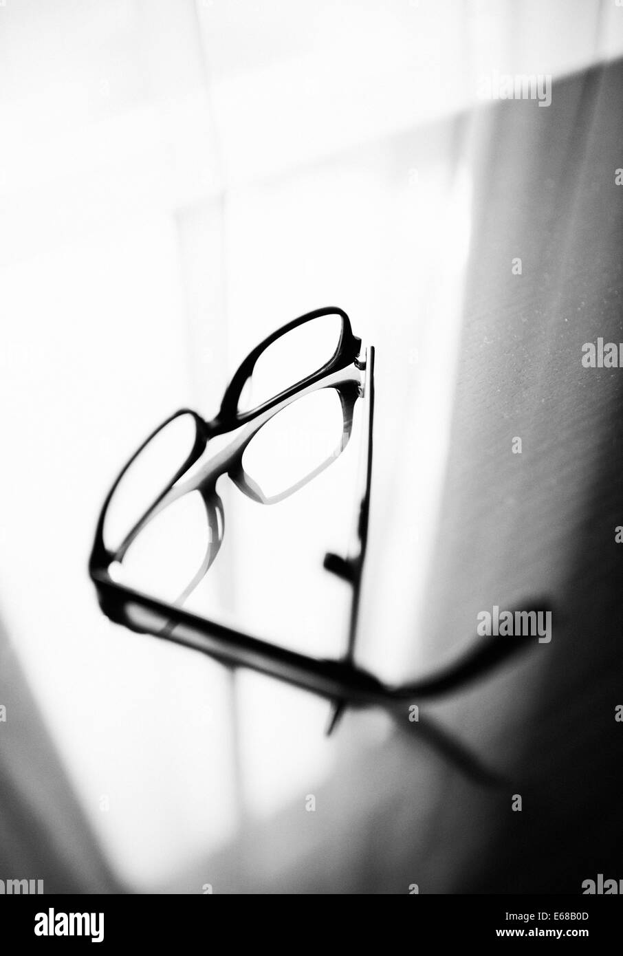 Les lunettes sur une table en verre en face de la fenêtre avec la réflexion des verres sur la surface. Banque D'Images