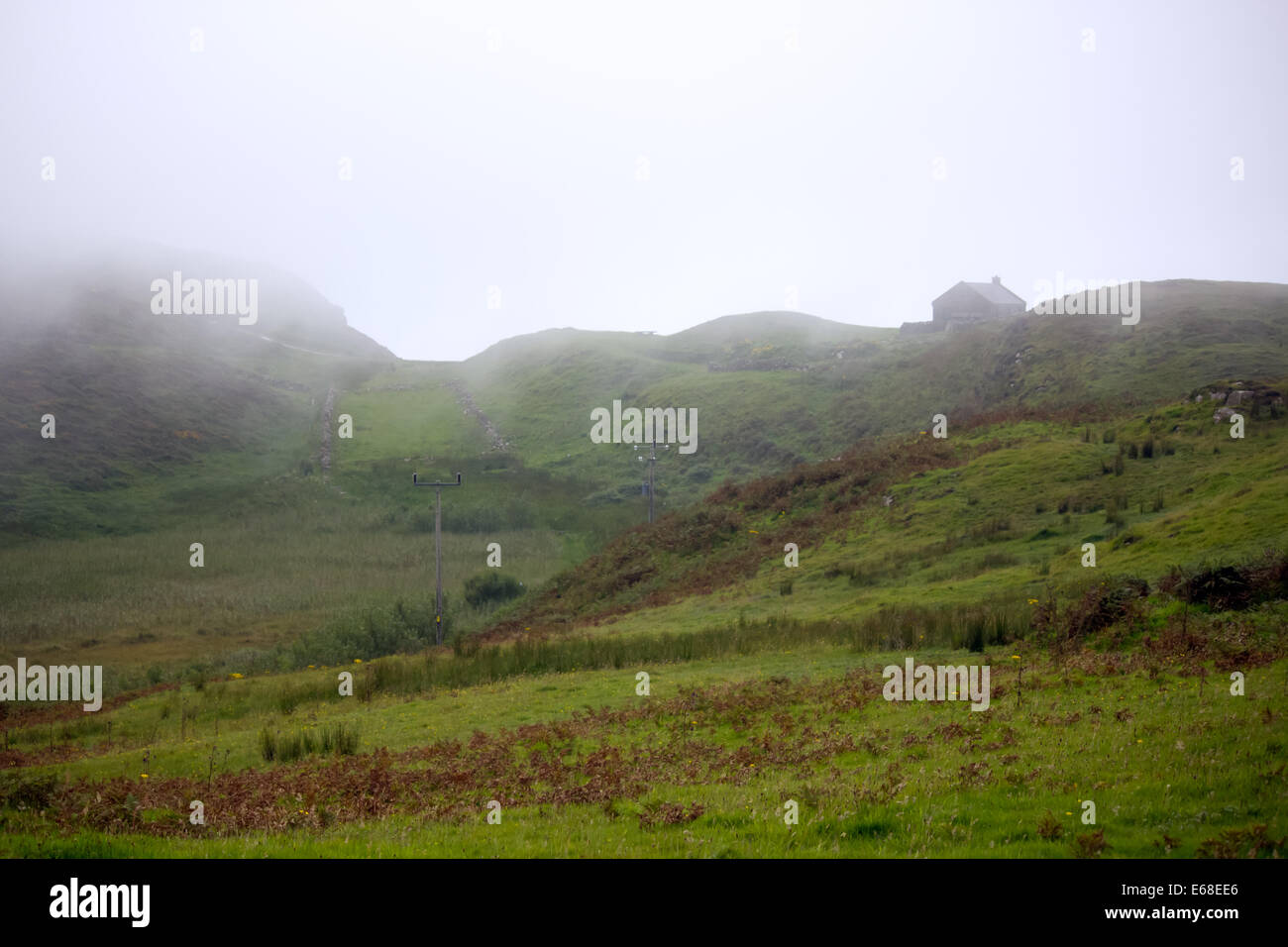 Le dirigeant d'une maison se trouve sur une colline avec vue sur les maures de l'Irlande du Nord de l'île de Rathlin. Un nuage de basse altitude couvre le réseau local Banque D'Images