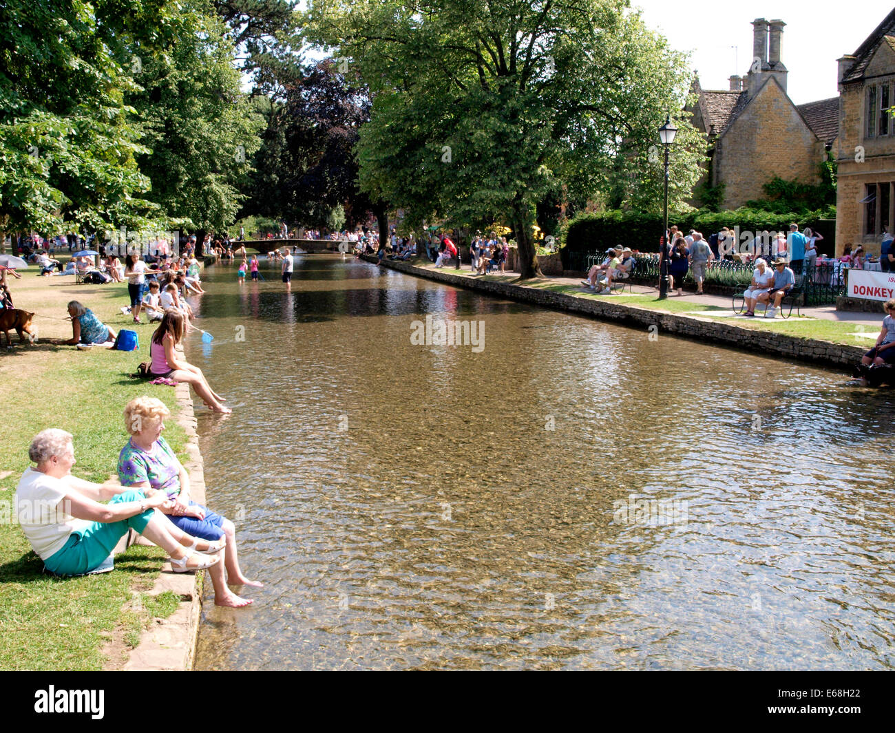 Les personnes bénéficiant de la canicule de l'été par la rivière Windrush, Bourton-on-the-water, Gloucestershire, Royaume-Uni 30/07/2014 Banque D'Images