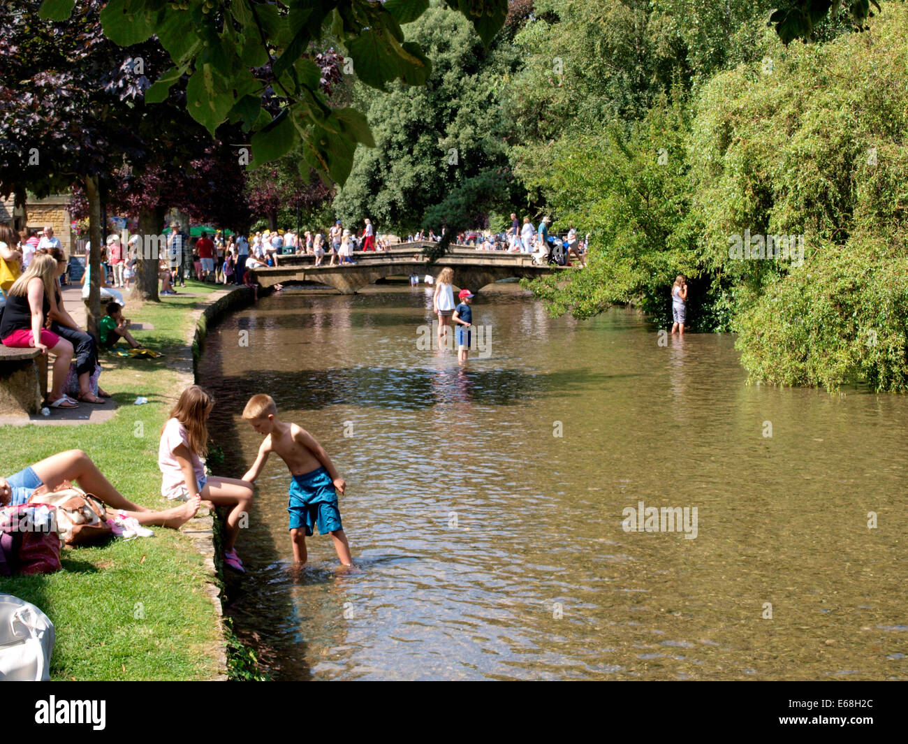 Les personnes bénéficiant de la canicule de l'été par la rivière Windrush, Bourton-on-the-water, Gloucestershire, Royaume-Uni 30/07/2014 Banque D'Images