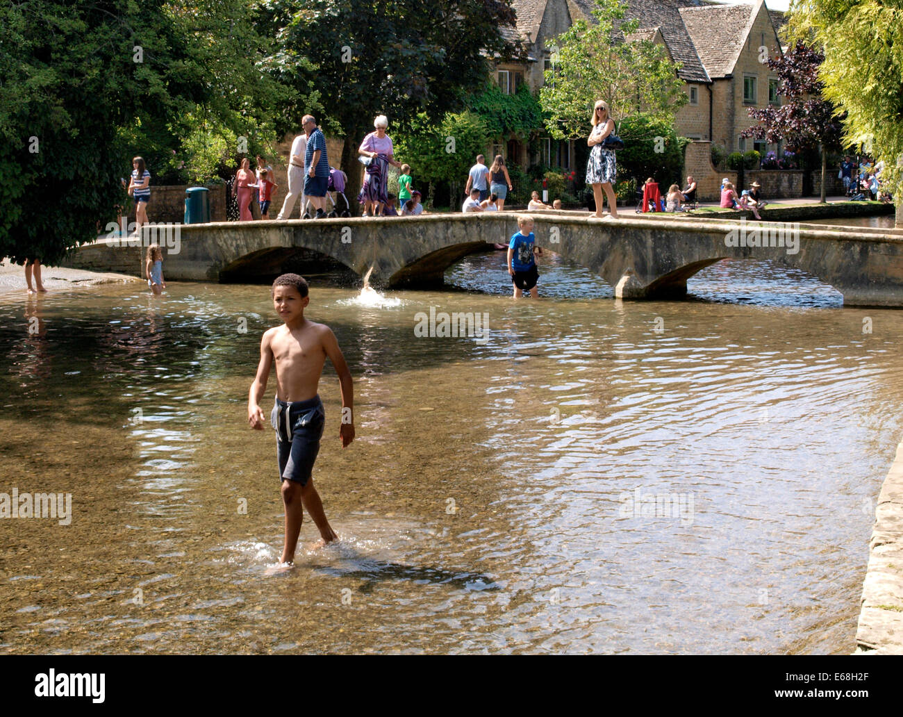 Les personnes bénéficiant de la canicule de l'été par la rivière Windrush, Bourton-on-the-water, Gloucestershire, Royaume-Uni 30/07/2014 Banque D'Images
