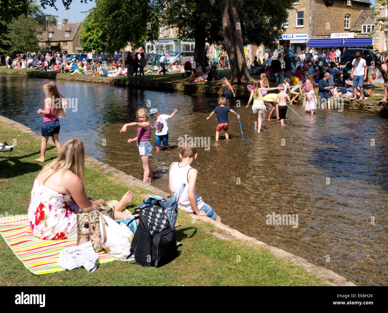 Les personnes bénéficiant de la canicule de l'été par la rivière Windrush, Bourton-on-the-water, Gloucestershire, Royaume-Uni 30/07/2014 Banque D'Images
