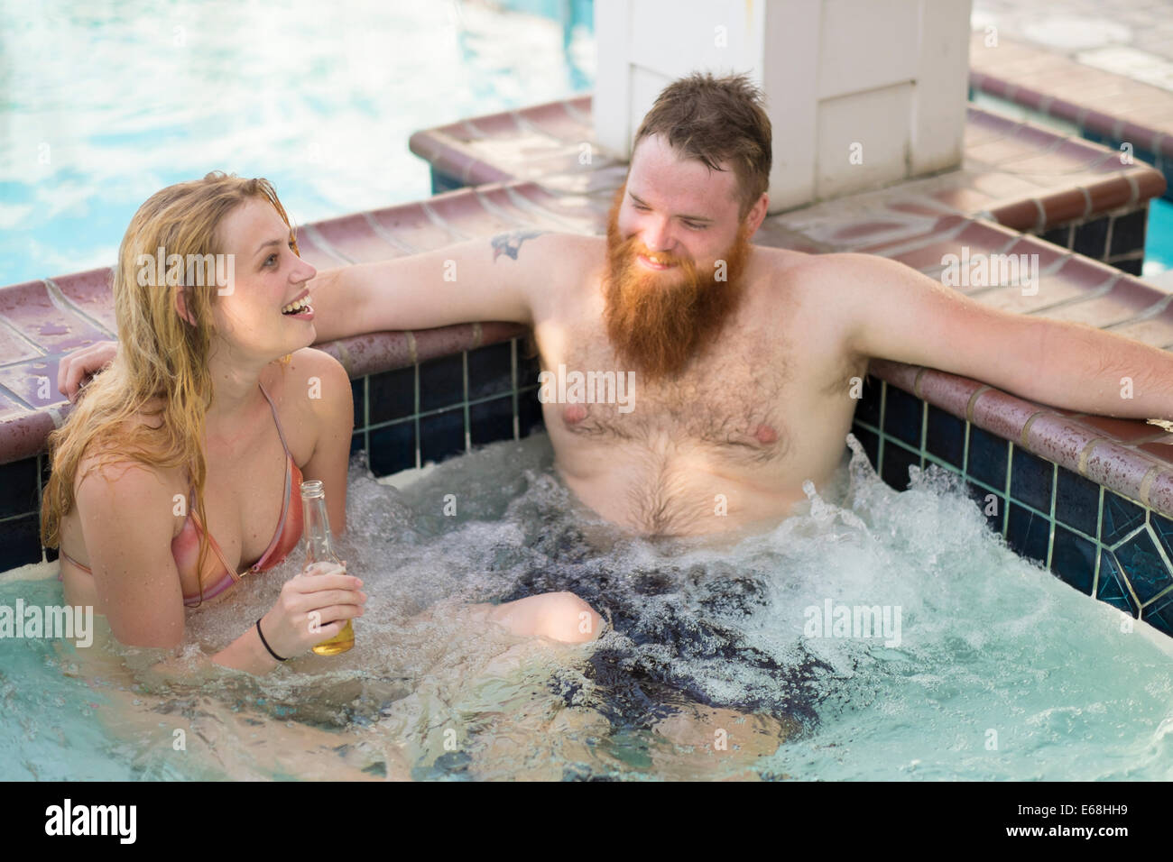 Jacuzzi dans espace bien-être de l'hôtel avec les jeunes adultes de boire une bière et de rire. Banque D'Images