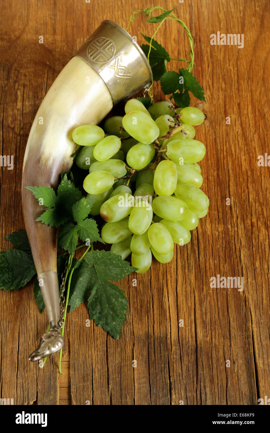 Les raisins mûrs brosse douce avec une corne potable traditionnel sur fond de bois Banque D'Images