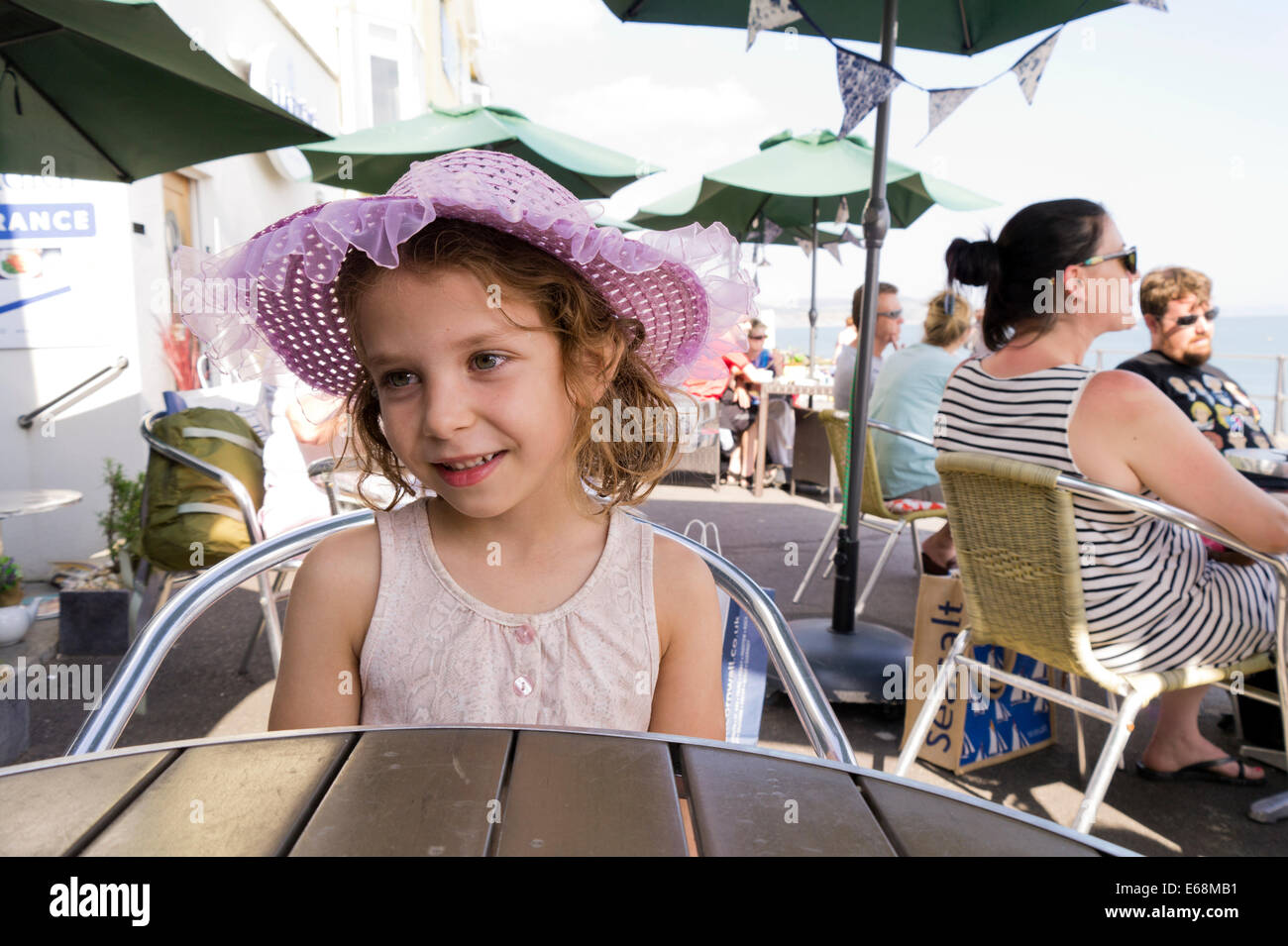 Enfant Jeune fille assise à table cafe de la chaussée. Lyme Regis, dans le Dorset. Banque D'Images