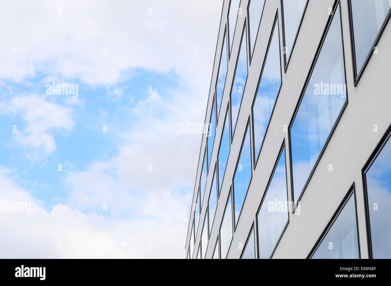 Ciel bleu et nuages reflétée dans les fenêtres en miroir du nouveau bâtiment moderne à la façade de verre. Arrière-plan avec copie libre-espace salon pour Banque D'Images