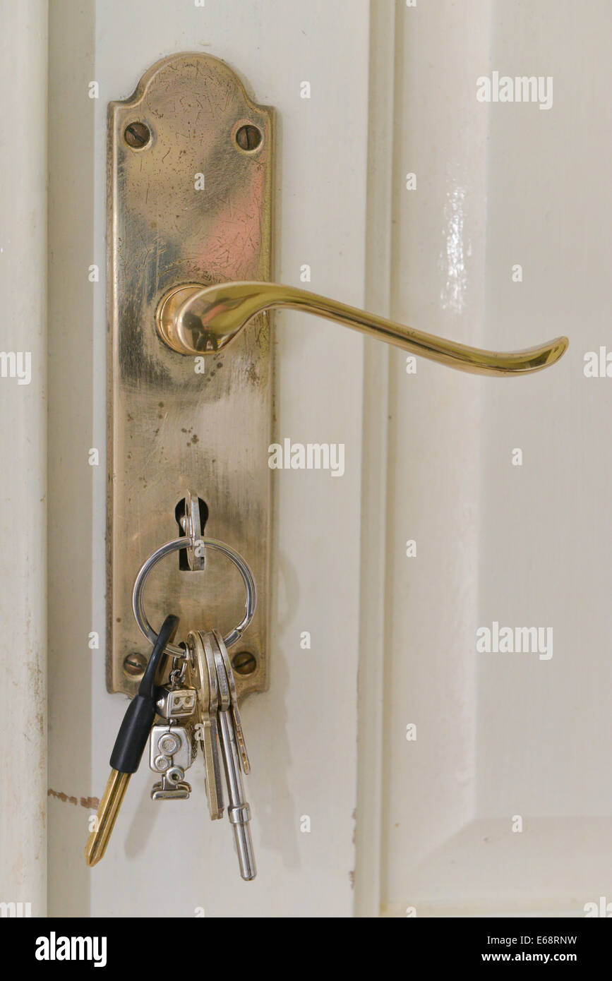 Poignée d'une porte avec un tas de clés dans la serrure d'une porte blanche Banque D'Images