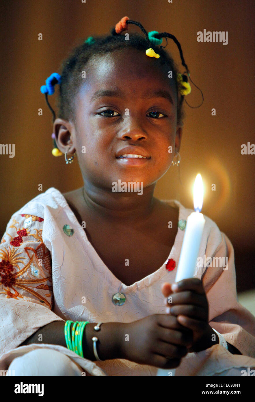 Fille (3 ans) maintenant bougie dans une église catholique à Kaolack, Sénégal, Afrique Banque D'Images