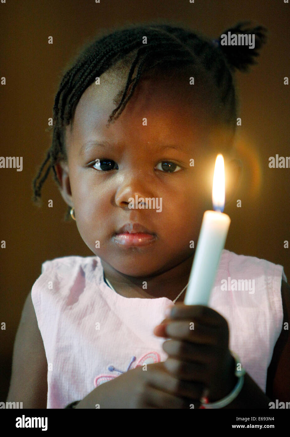 Girl (2 ans) maintenant bougie dans une église catholique à Kaolack, Sénégal, Afrique Banque D'Images
