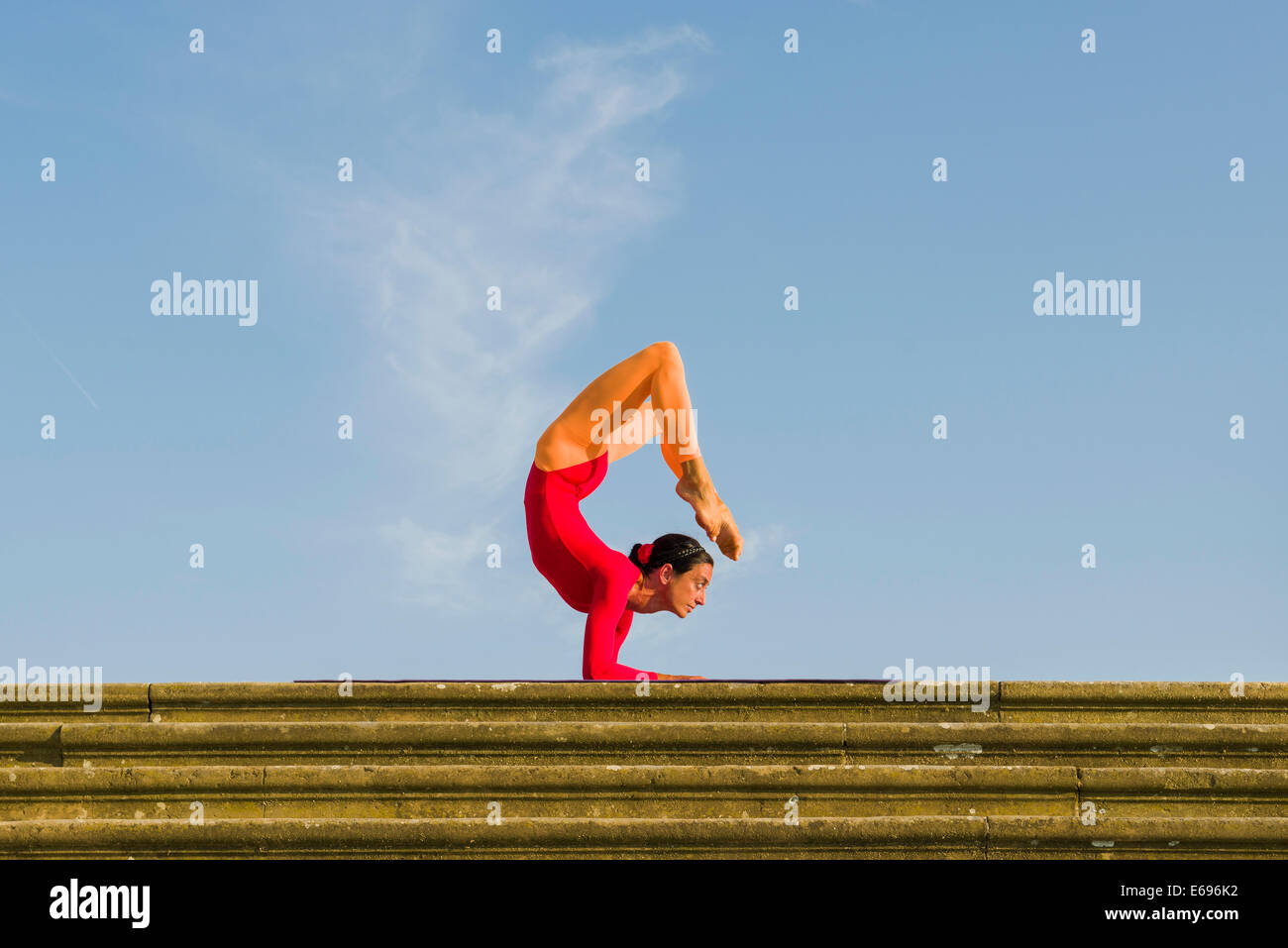Jeune femme la pratique de l'Hatha Yoga, à l'extérieur, montrant la pose Vrischikasana Scorpion, poser Banque D'Images