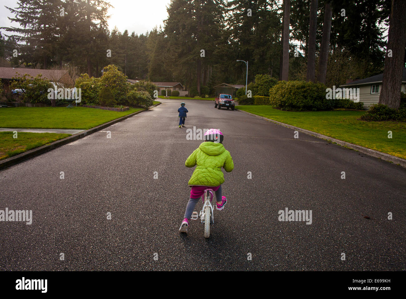 Des enfants de race blanche la bicyclette sur rue de banlieue Banque D'Images