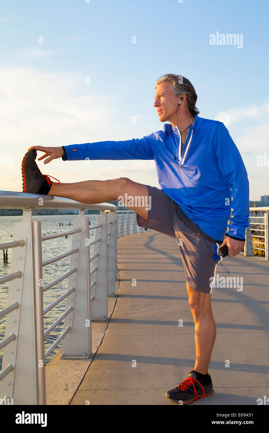 Caucasian runner stretching on urban waterfront Banque D'Images