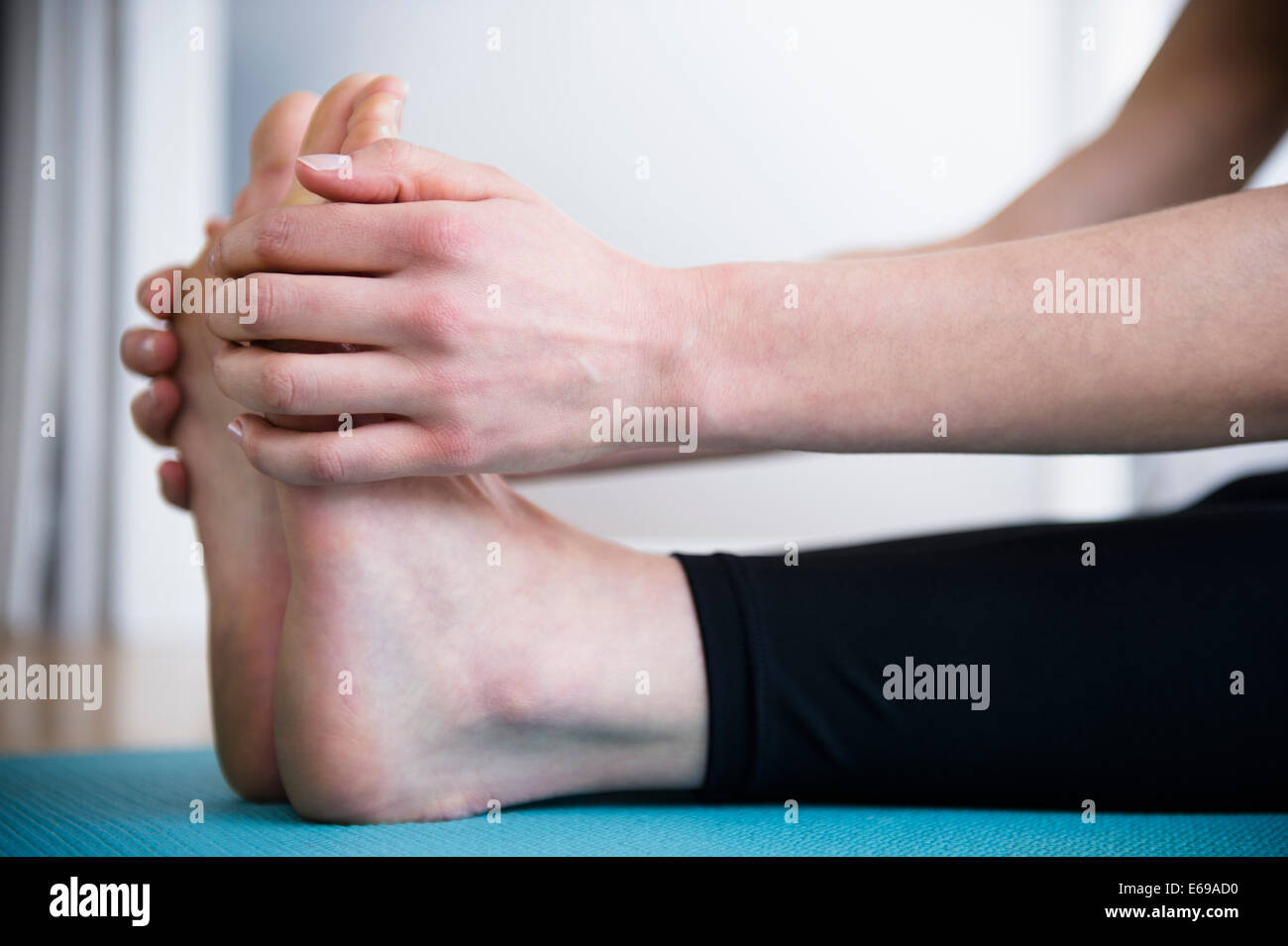 Caucasian woman stretching jambes on yoga mat Banque D'Images