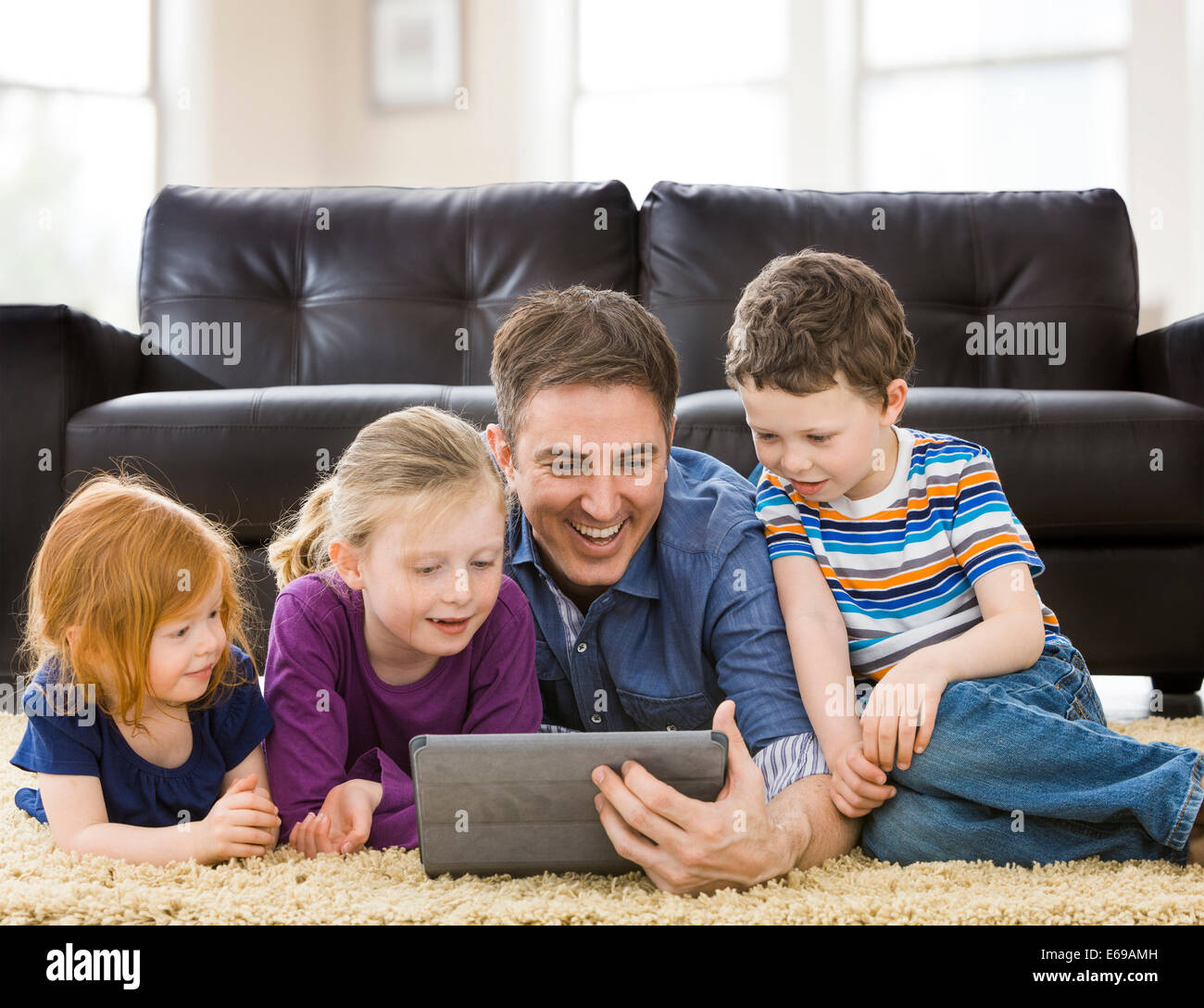 Woman and children using tablet computer in living room Banque D'Images