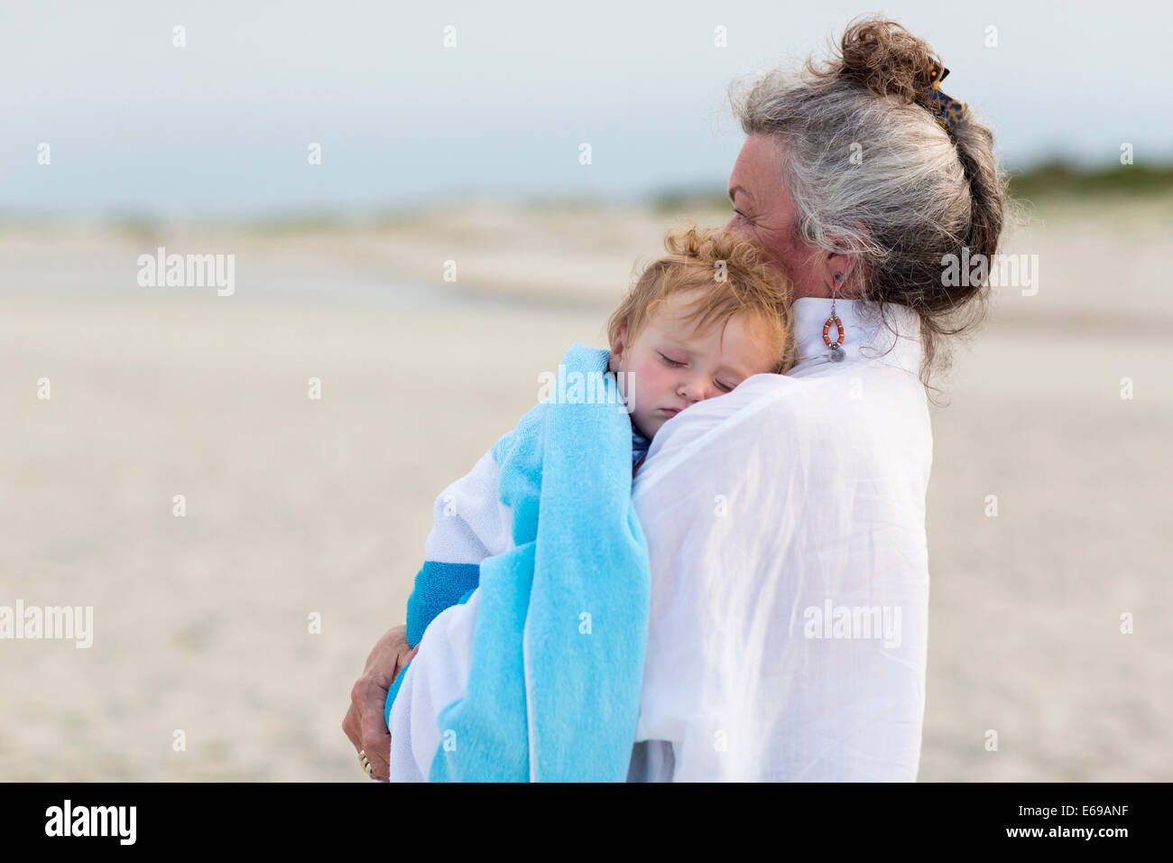 Caucasian woman exerçant son petit-fils sur la plage Banque D'Images