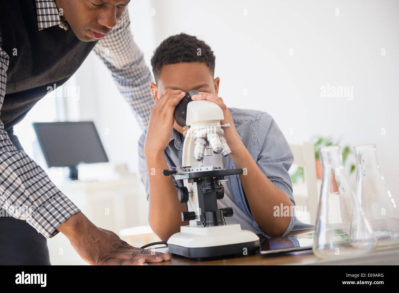 Aider les élèves à utiliser l'enseignant dans la classe de sciences microscope Banque D'Images