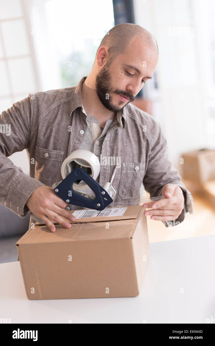 Man taping cardboard box Banque D'Images