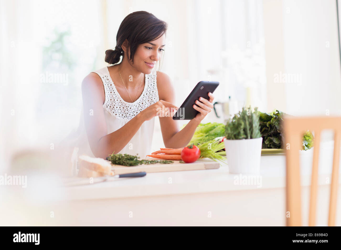 Hispanic woman cooking with digital tablet Banque D'Images