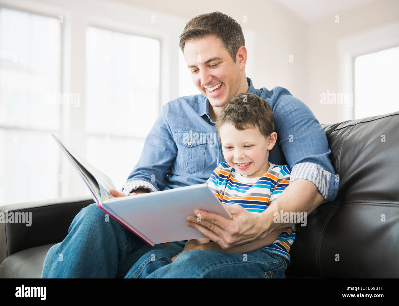 Portrait père et fils lecture sur canapé Banque D'Images