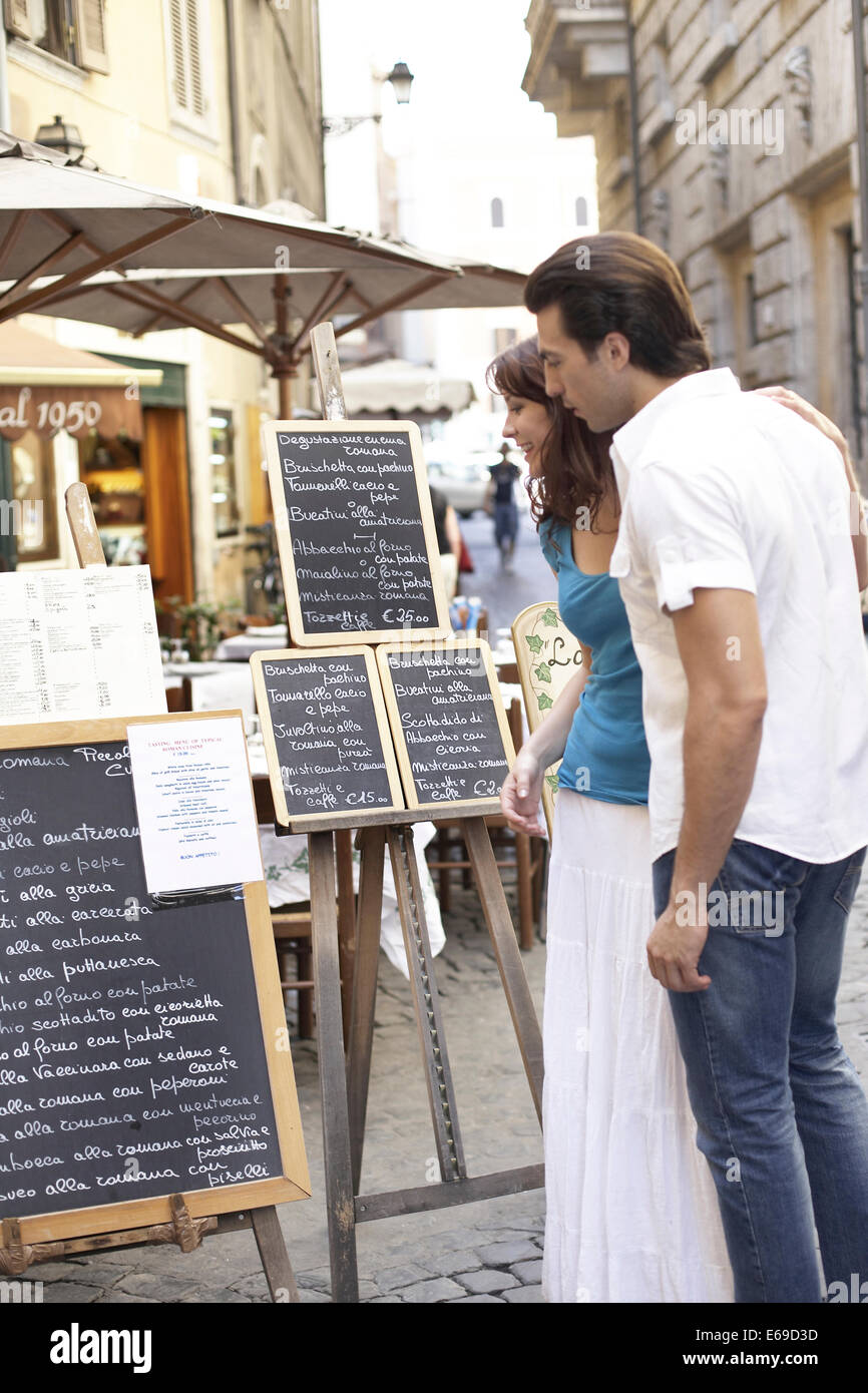 Caucasian couple lecture des menus on city street Banque D'Images