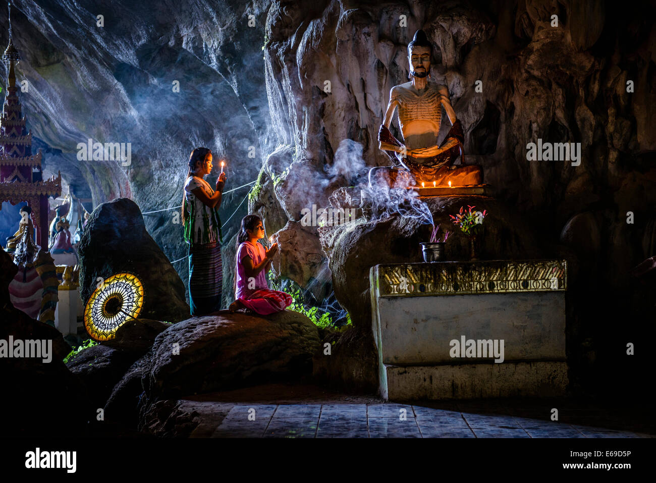 Filles asiatiques éclairant l'encens dans le temple de grotte Banque D'Images