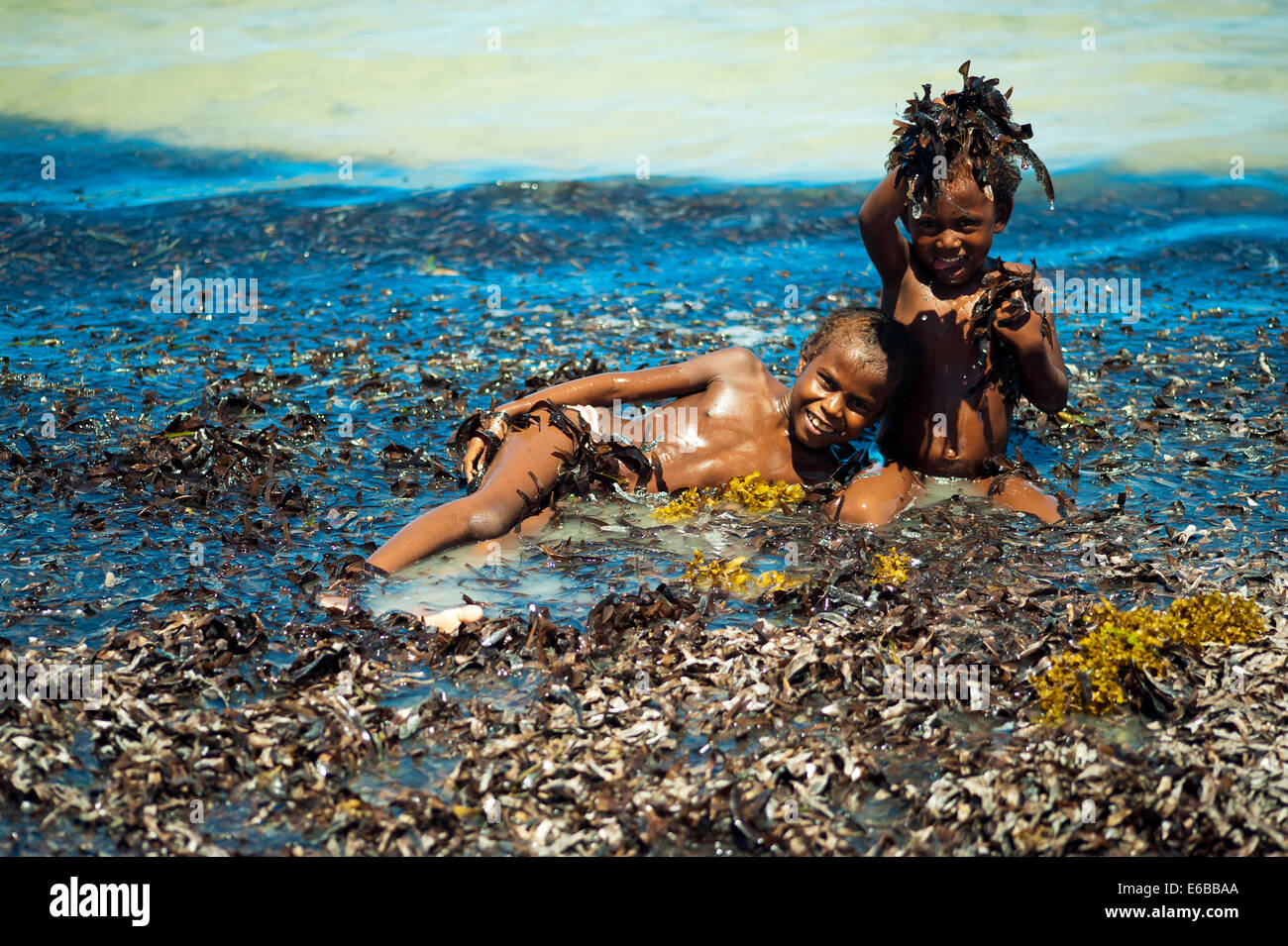 Madagascar, Tuléar, Ifaty, de jeunes enfants jouant avec des algues sur la plage. Banque D'Images