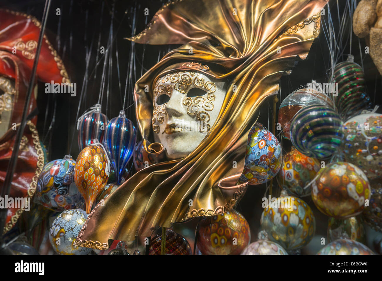 Or élégant masque de carnaval vénitien entouré par les ornements de verre dans un magasin sur l'une des principales artères de Venise. Banque D'Images