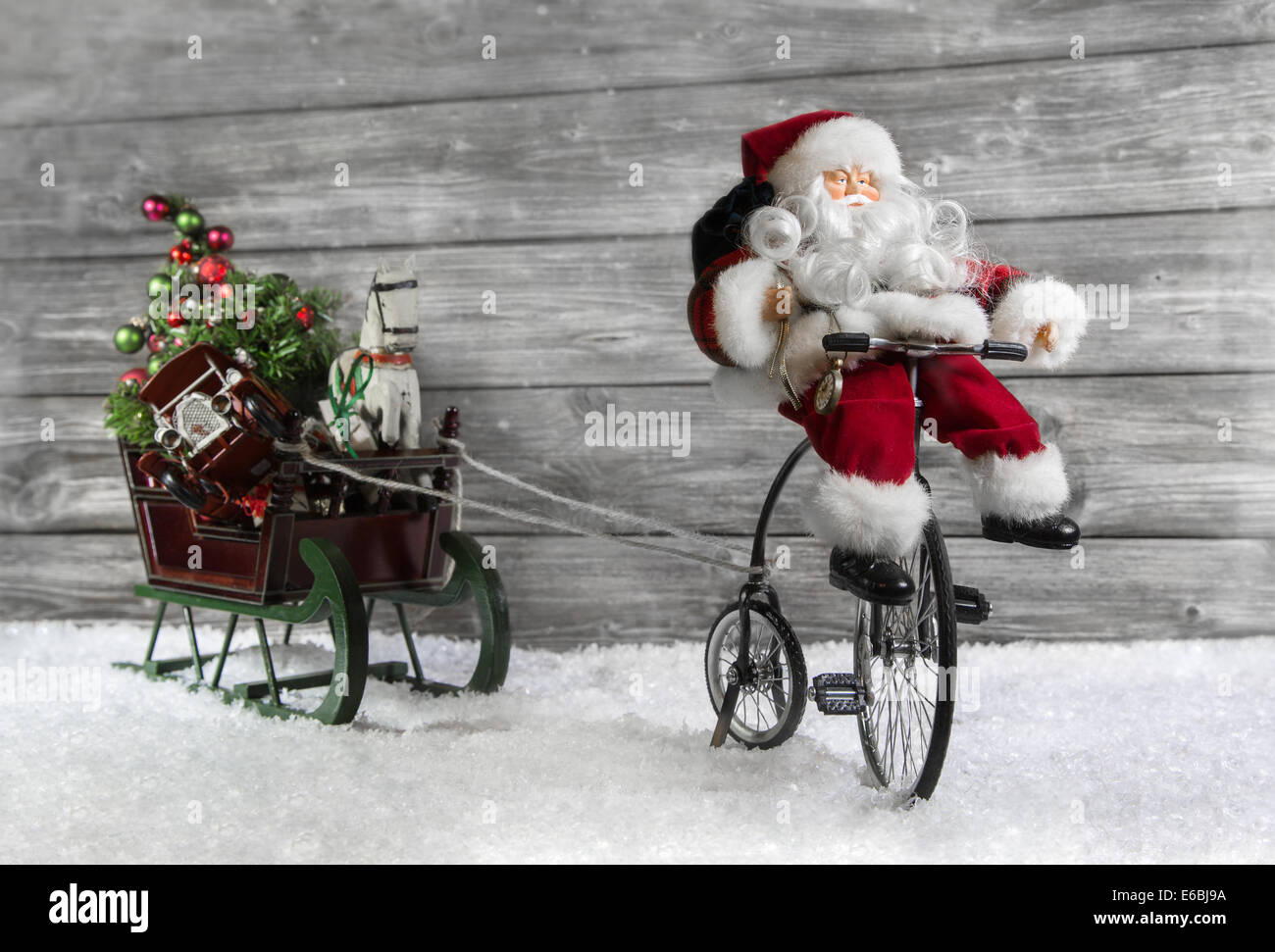 Carte de vœux de noël drôle avec le Père Noël sur un vélo tirant une diapositive dans la neige. Banque D'Images