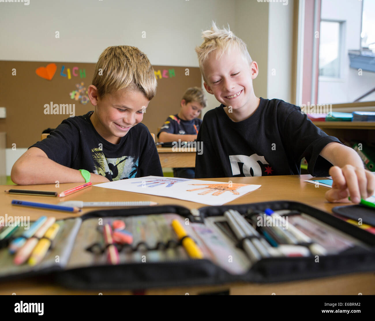 Smiling Children assis dans une classe de l'école primaire au cours d'une leçon de dessin, Reith im Alpbachtal, district de Kufstein, Tyrol Banque D'Images