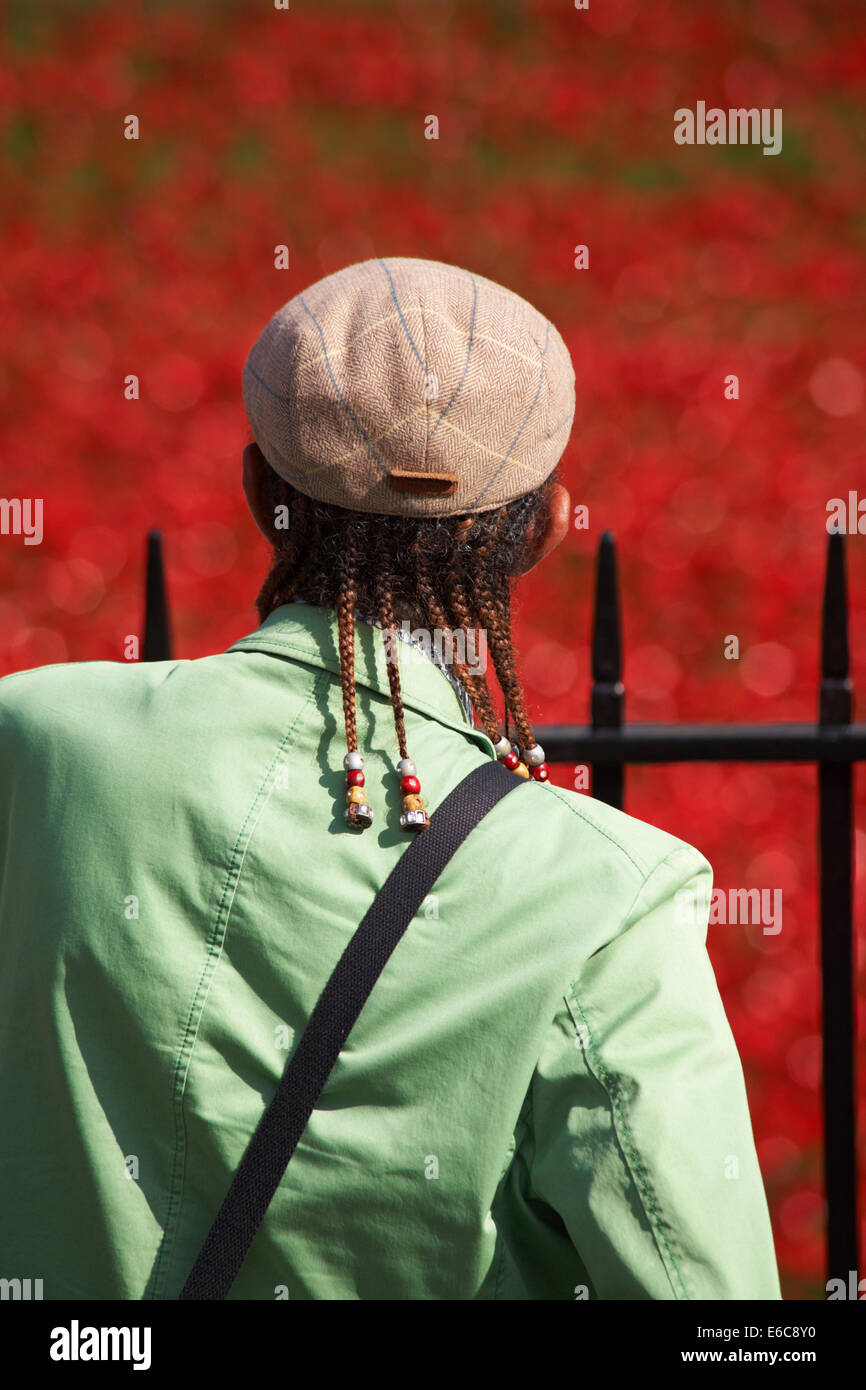 Homme afro-caribéen regardant des coquelicots en céramique des terres balayées par le sang et des mers rouges à la Tour de Londres, au Royaume-Uni pour marquer le centenaire de la première Guerre mondiale Banque D'Images