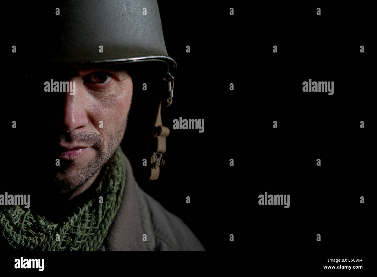 La Seconde Guerre mondiale, soldat américain, avec la moitié de son visage dans l'ombre et, debout devant un fond noir. Banque D'Images