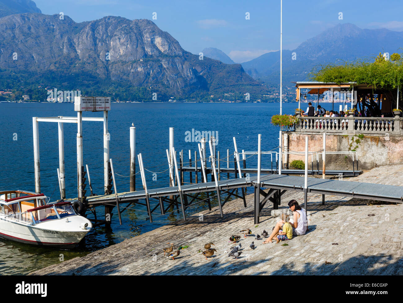 Mère et fils se nourrir les canards et les pigeons sur le bord du lac à Bellagio, Lac de Côme, Lombardie, Italie Banque D'Images