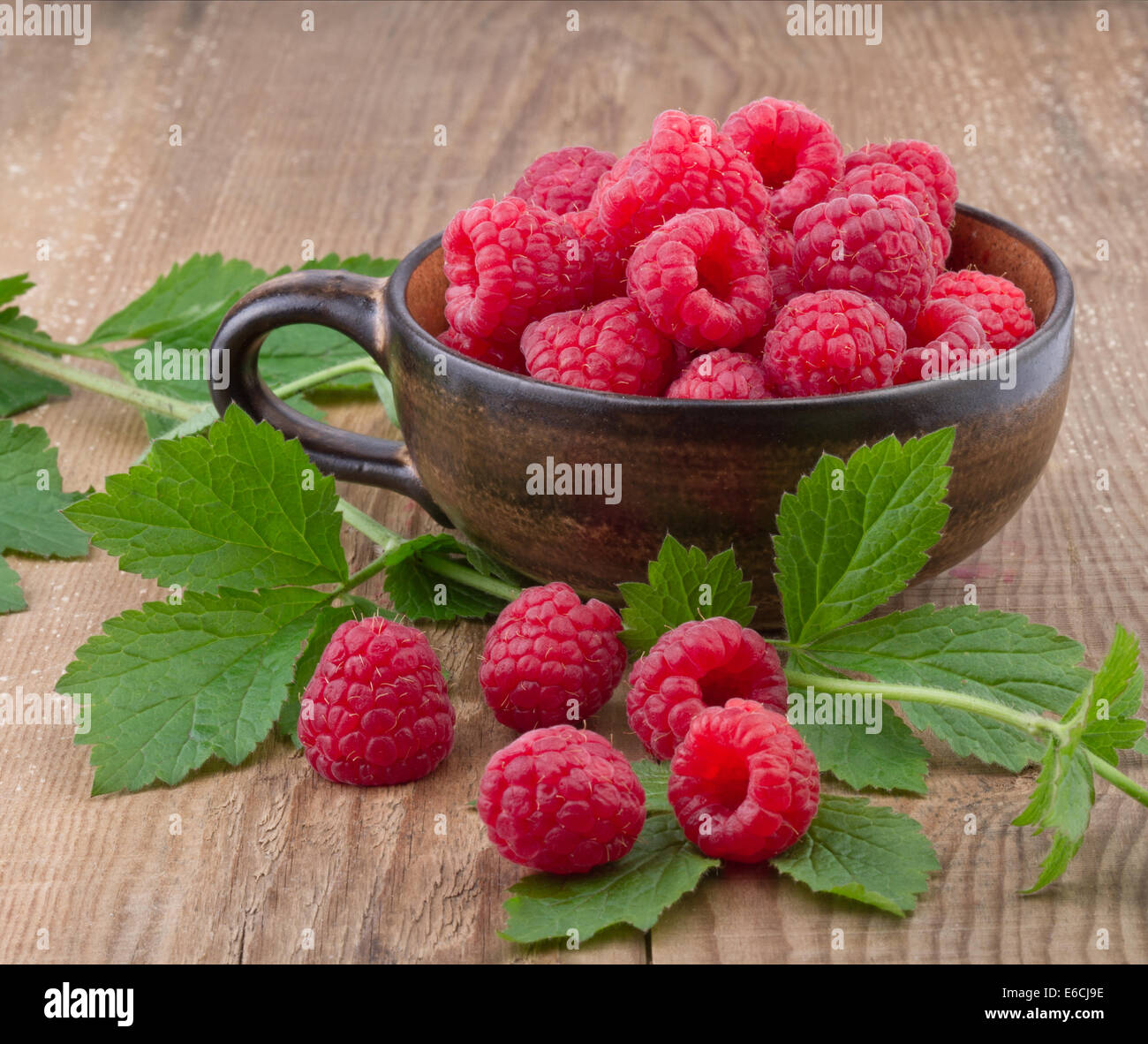 Dans une tasse de framboises sur table en bois Banque D'Images