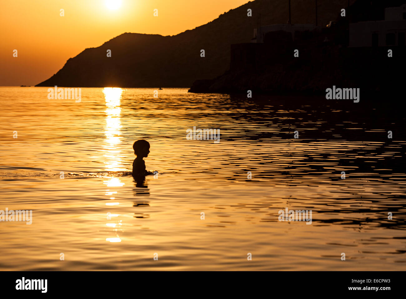 Silhouette d'un garçon marche dans la mer. Banque D'Images