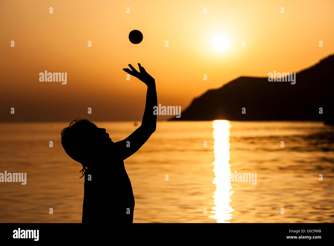 Silhouette d'un garçon en train de lancer balle en l'air Banque D'Images