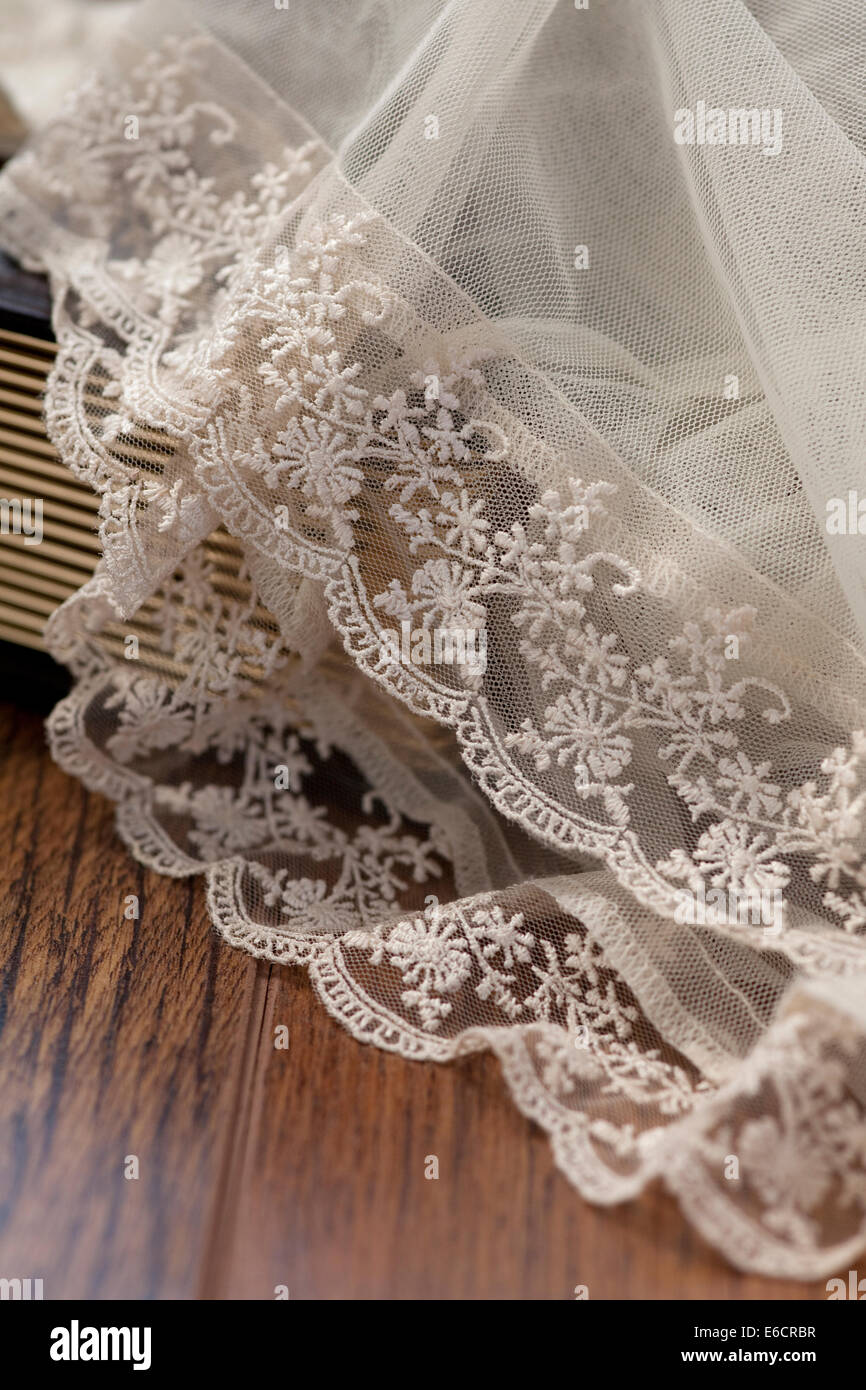 White lace Bridal Veil drapé sur un plancher en bois et des pages d'un livre. Banque D'Images