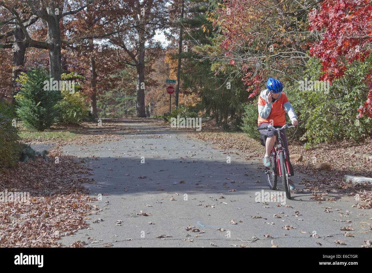 Jeune femme parlant sur un téléphone cellulaire pendant le vélo et ne pas payer l'attention sur le beau paysage d'automne autour d'elle Banque D'Images