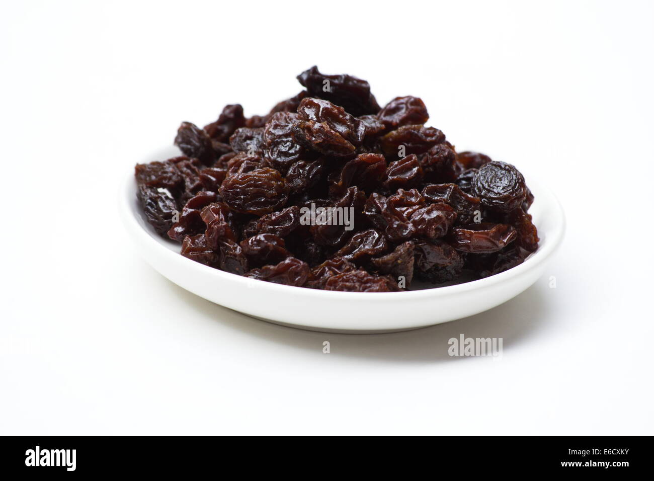 Les raisins secs dans un plat blanc sur fond blanc Banque D'Images