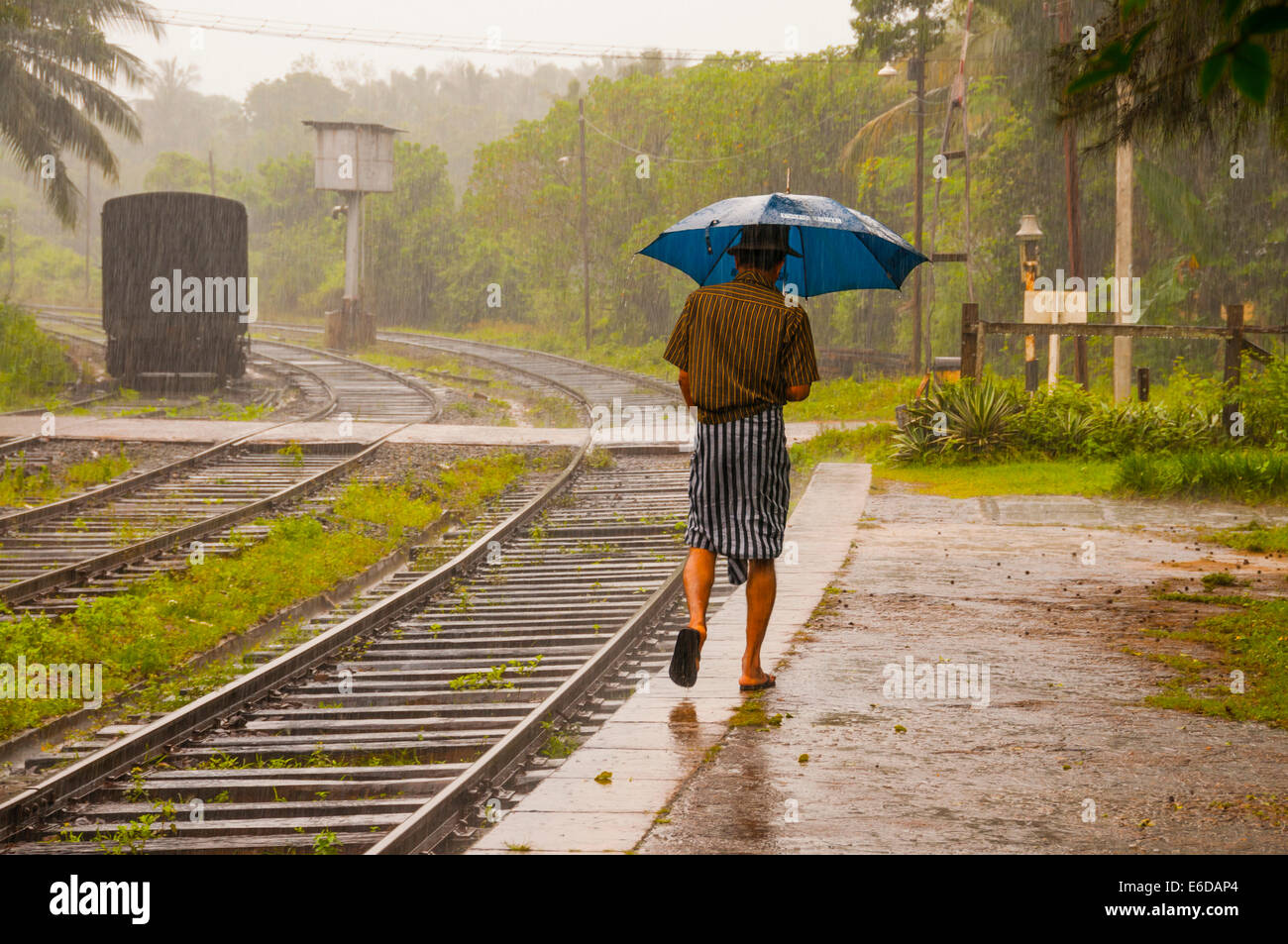 Sri Lanka, district d'Anuradhapura, Kalawewa, Cingalais marche à travers la pluie de mousson à la gare Banque D'Images