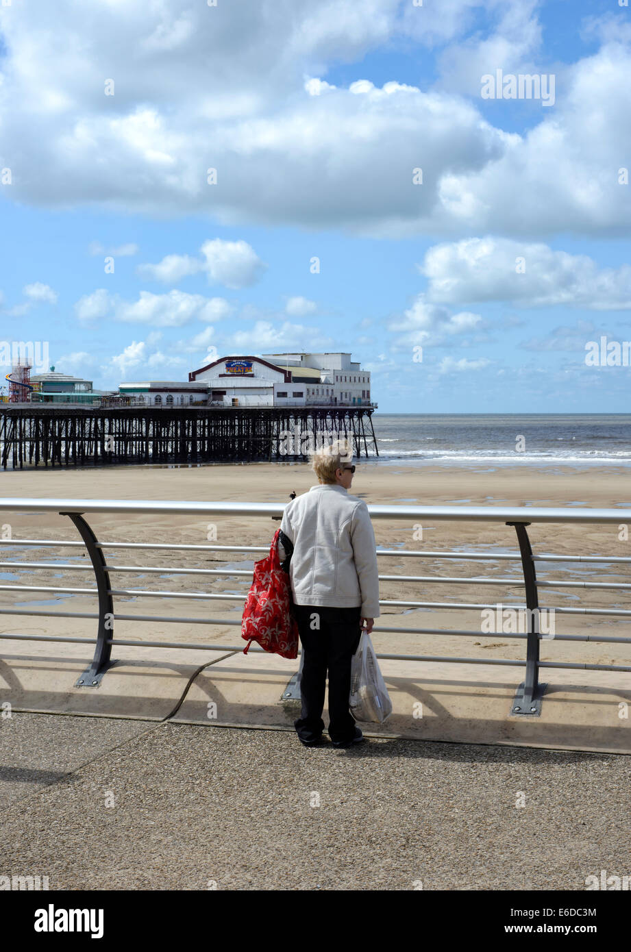 Femme plus âgée solitaire à la recherche de l'autre côté de la plage et de la mer de Blackpool, Lancashire, Angleterre Banque D'Images
