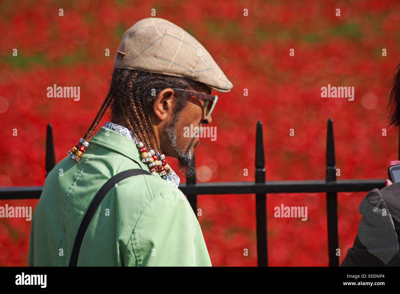 Homme afro-caribéen regardant des coquelicots en céramique des terres balayées par le sang et des mers rouges à la Tour de Londres, au Royaume-Uni pour marquer le centenaire de la première Guerre mondiale Banque D'Images