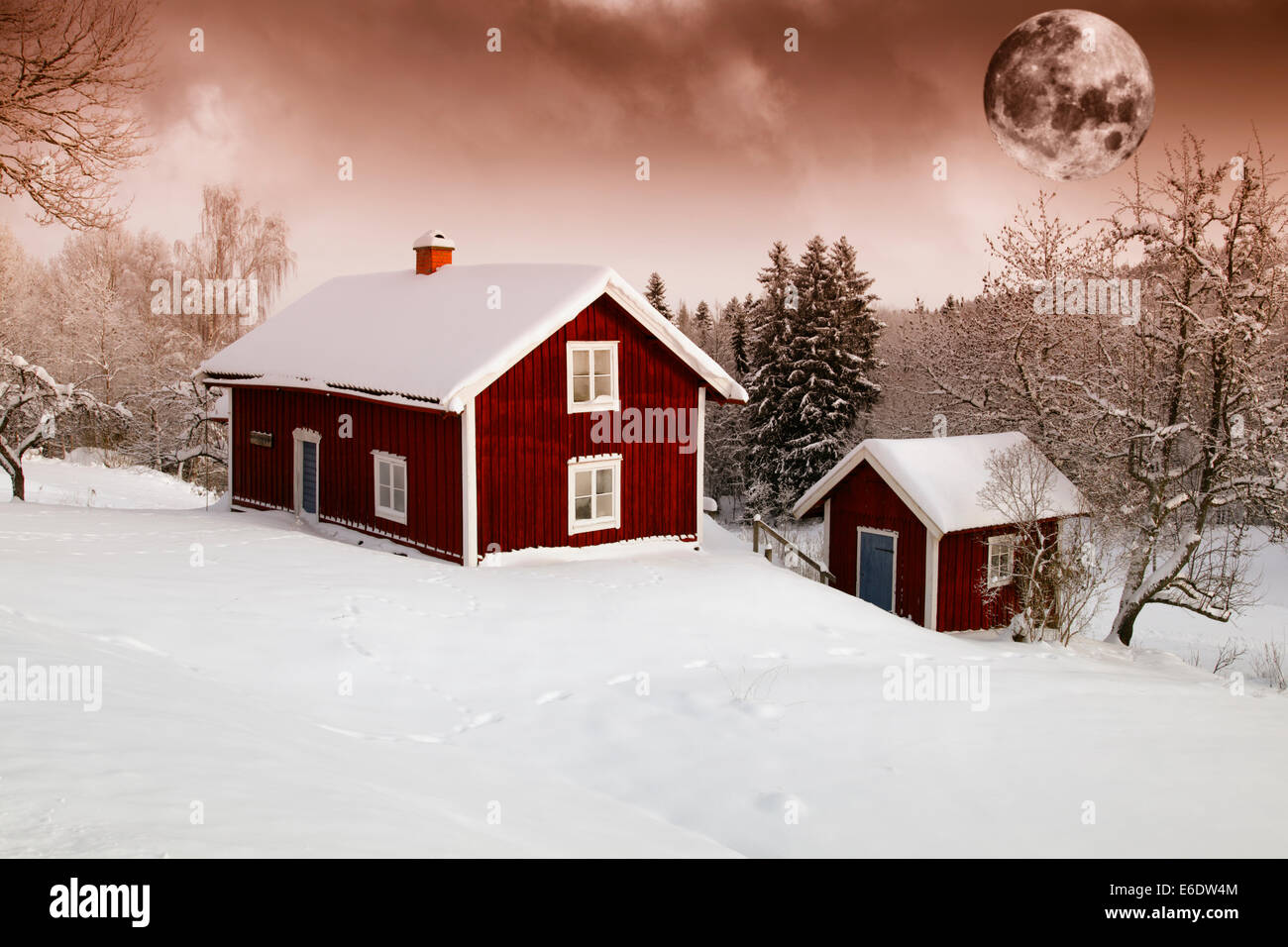 Lune rouge au cours de l'hiver de neige et de cottages Banque D'Images